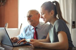 Jeune femme avec un homme âgé sur PC avec carte de crédit