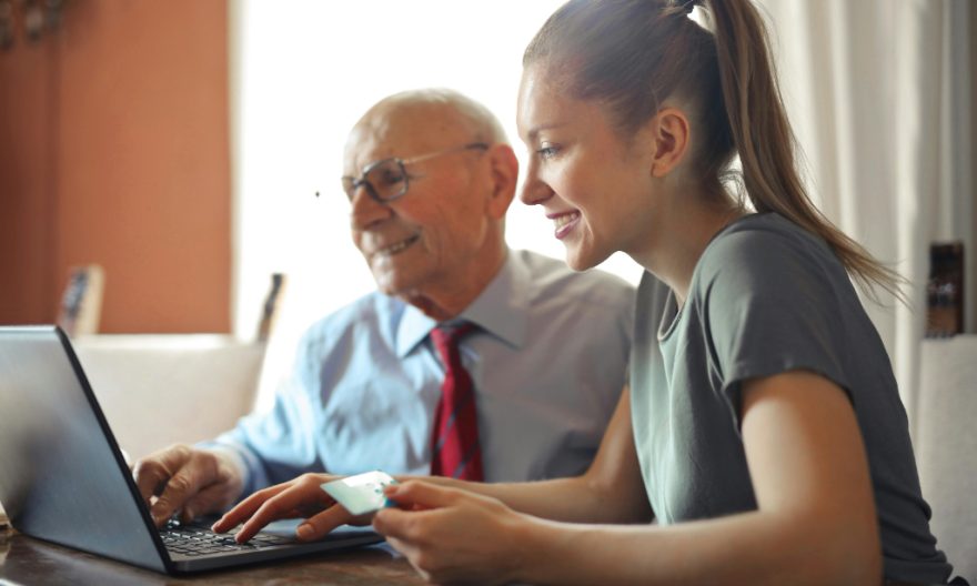 Jeune femme avec un homme âgé sur PC avec carte de crédit